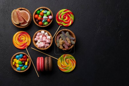 Photo for Various colorful candies, lollipops, and macaroons. Flat lay over stone background with copy space - Royalty Free Image