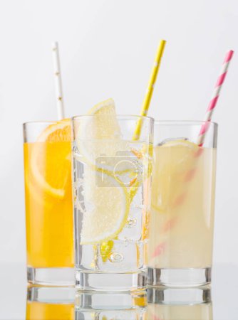 Verschiedene Limonade mit Eis in Gläsern vor grauem Hintergrund