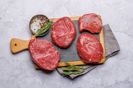 Raw beef fillet steaks on a cutting board, fresh and uncooked. Flat lay