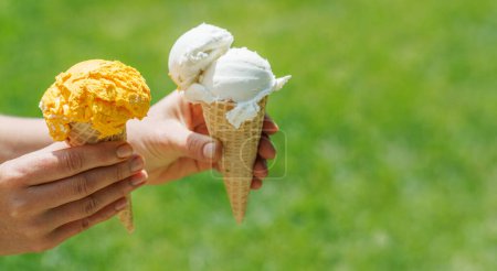 Foto de Las manos de la mujer sosteniendo refrescante helado en conos de gofre trata con un toque de sabor a limón picante. Con espacio de copia - Imagen libre de derechos