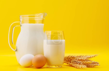Téléchargez les photos : Pichet de lait aux œufs sur fond jaune avec espace de copie - en image libre de droit