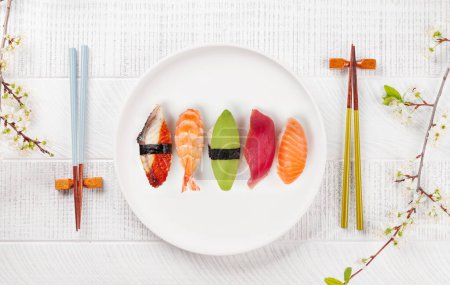 Foto de Placa de sushi en la mesa adornada con ramas de flor de cerezo y palillos, personificando la cultura alimentaria japonesa - Imagen libre de derechos