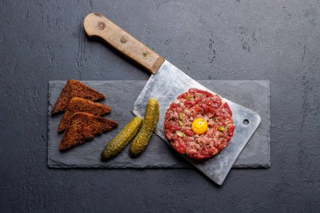 Savory beef tartare with pickled gherkins and brown bread toasts. Flat lay