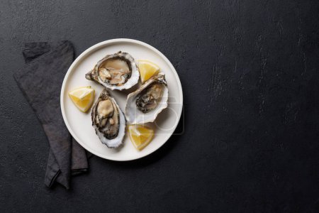 Fresh oysters with lemon on plate. Flat lay with copy space