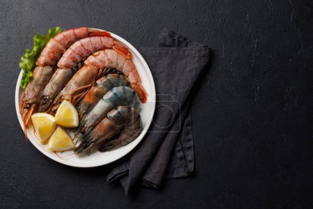 Téléchargez les photos : Crevettes crues sur assiette, prêtes à cuire. Pose plate avec espace de copie - en image libre de droit