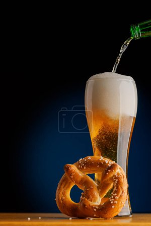 Beer on the bar: Refreshing draft brew and pretzel on a wooden table. With copy space