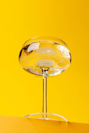 Champagner-Eleganz: Glas mit Sekt vor leuchtendem gelben Hintergrund. Mit Kopierraum