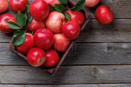 Wooden box with fresh red apples on wood table. Flat lay with copy space