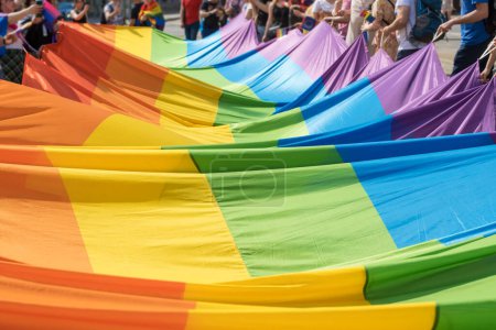 Photo for Unidentified people holding huge rainbow flag during LGBT pride. Pride community celebrating love and diversity carrying big flag during lesbian gay bisexual and transgender march. - Royalty Free Image