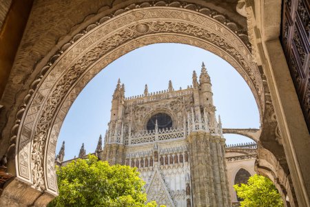 Téléchargez les photos : Cathédrale de Séville vue à travers la belle arche sculptée par une journée ensoleillée en été à Séville, Andalousie, Espagne - en image libre de droit