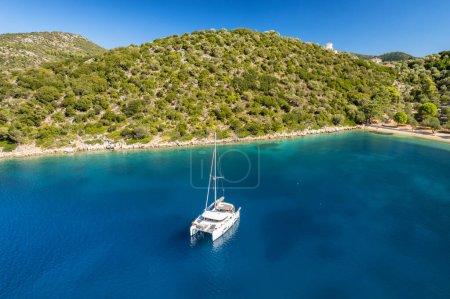Luftaufnahme eines festgemachten Yachtbootes in einer wunderschönen ruhigen Meeresbucht mit türkisfarbenem Wasser in der Nähe des Strandes von Dexia auf der Insel Itaca, Griechenland. Luxus-Katamaran-Jacht in Ithaki, Kefalonia, Ionisches Meer.