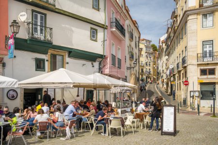 Téléchargez les photos : Lisbonne, Portugal - 2 avril 2022 : Café de rue avec des tables à l'extérieur et des gens qui boivent et discutent entre eux. - en image libre de droit