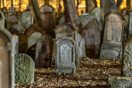 Photo for Tombstones in an old cemetery at night. Blanketed gravestones create a spooky scene. Leaning tombstones add to the eerie ambience in a dark autumn setting. Creepy aged tombstones in the graveyard. - Royalty Free Image