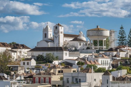 Tavira town cityscape, Algarve region, Portugal. Clock tower, St Marys church and traditional portuguese buildings at sunny day in Tavira