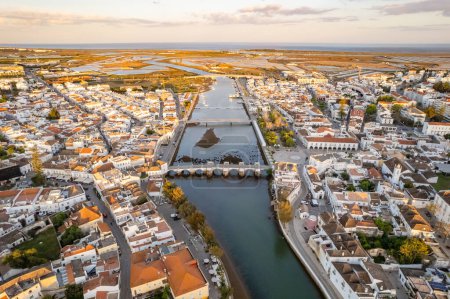 Photo for City center of the Tavira town in morning sunlight, Portugal. Aerial view of the Tavira old town at sunrise, Algarve region, Portugal. Central square, Ponte Romana bridge and historic buildings. - Royalty Free Image