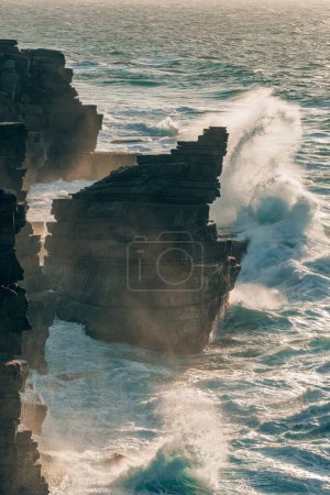 Photo for Ocean wave breaking on a rocky shore with rough sea water in Portugal. Cliffs on the dramatic Portuguese coast with Atlantic ocean waves crash against the rugged shoreline - Royalty Free Image