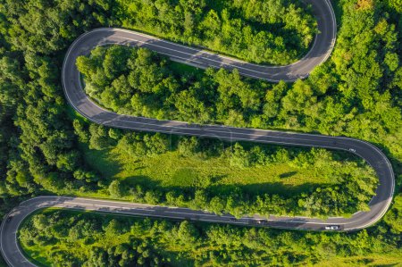 Photo for Aerial summer view of a winding mountain road forming an S-shape. This scenic route traverses the Bieszczady Mountains in Poland. Top down view. Winding mountain road in forest - Royalty Free Image