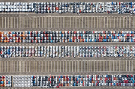 Luftaufnahme von Neuwagen, die zum Verkauf in einer Reihe von Lagerplätzen geparkt sind. Händlerinventar für Import und Export im globalen Automobilgeschäft. Distribution und Logistik in der Automobilindustrie