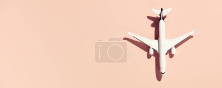 Photo for Miniature white airplane on a pink background. Banner, flat lay, creative concept of air transportation, tourism, travel. Copy space for text - Royalty Free Image
