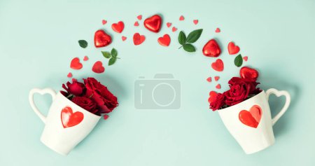 Téléchargez les photos : Two cute cups with roses, gift boxes, chocolate and red hearts on blue background, top view, flat lay, banner. Valentines day, Wedding, Anniversary concept - en image libre de droit