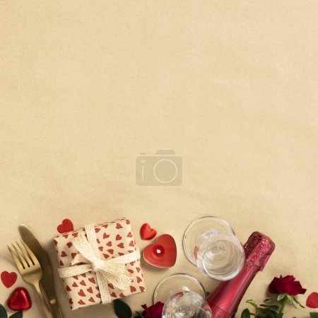 Photo for Valentines day composition with gift box in craft recycling paper, roses, candles, cutlery, champagne, chocolate and wooden letters, top view, flat lay - Royalty Free Image