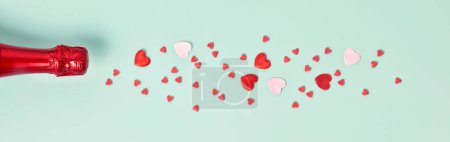 Foto de Champagne bottle with hearts on blue background, top view, flat lay, banner. Valentines day and party concept - Imagen libre de derechos