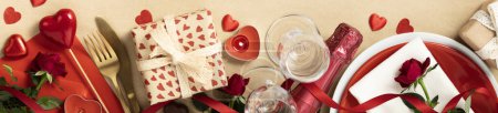 Photo for Valentines day composition with gift box in craft recycling paper, roses, candles, cutlery, champagne, chocolate and wooden letters, top view, flat lay, banner - Royalty Free Image
