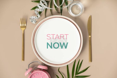 Téléchargez les photos : Quote Start now Composition with cutlery, plate, measuring tape, water and alarm clock on color background, Motivational and inspirational quote concept diet healthy life - en image libre de droit