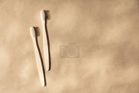Foto de Dos cepillos de dientes de madera natural sobre fondo beige natural con sombras de hojas, plano, vista superior. Concepto de cero residuos y cuidado dental natural. Copiar espacio - Imagen libre de derechos