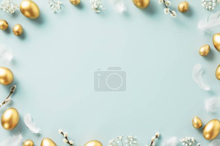 Téléchargez les photos : Décoration de table de Pâques. Joyeux concept de Pâques avec des œufs de Pâques dorés, des plumes et des fleurs de printemps sur fond bleu. Espace de copie de vue de dessus plat - en image libre de droit