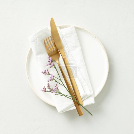 Foto de Gold Cutlery with eucalyptus branches on white plate with napkin over light grey Background. Minimalistic design. Copy Space - Imagen libre de derechos