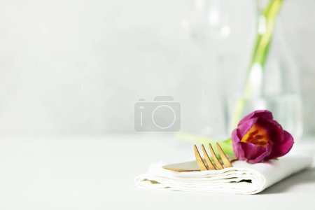 Téléchargez les photos : Ensemble de couverts dorés et belle fleur sur table gris clair avec espace pour le texte. Réglage de la table festive - en image libre de droit