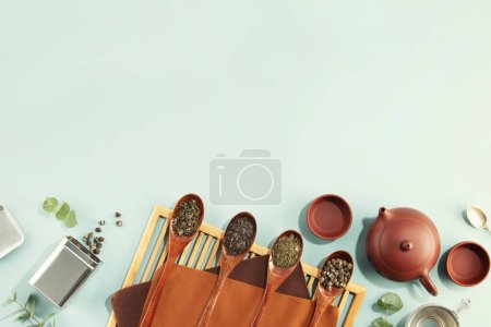 Téléchargez les photos : Bel ensemble pour cérémonie du thé traditionnel et collection de thé dans des cuillères en bois sur fond bleu clair plat - en image libre de droit