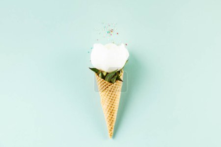 Foto de Bodegón creativo de cono de gofre con flor de peonía sobre fondo azul claro pastel, vista superior. Concepto mínimo de verano - Imagen libre de derechos