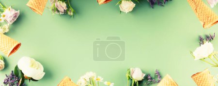 Photo for Flat-lay of waffle cones and flowers over pastel green background, top view, flat lay. Spring or summer mood concept, banner, copy space - Royalty Free Image