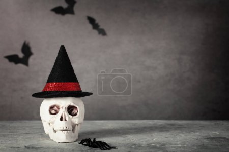 Photo for Halloween holiday concept with scull wearing witch hat. Minimal surreal creative concept for Halloween celebration banner or advertisement. Halloween background, copy space - Royalty Free Image