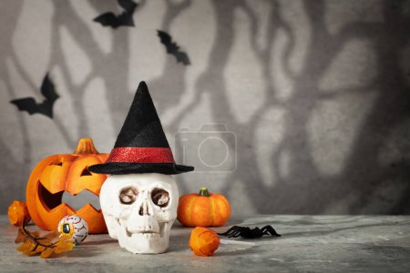 Téléchargez les photos : Concept de vacances d'Halloween avec scull portant un chapeau de sorcière. Concept créatif surréaliste minimal pour la bannière de célébration d'Halloween ou la publicité. Halloween fond, espace de copie - en image libre de droit