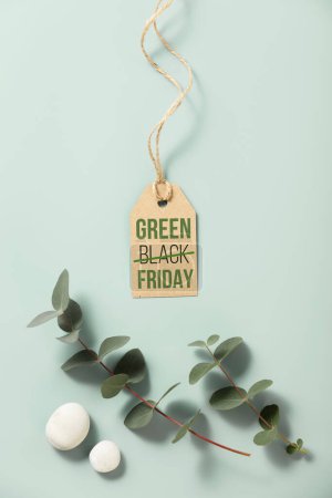 Foto de Etiqueta de venta con inscripción Green Black Friday rodeado de eucaliptos y piedras sobre fondo azul. Hacer viernes verde de nuevo. - Imagen libre de derechos