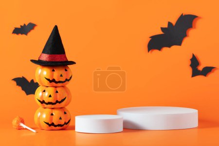 Foto de Composición creativa de Halloween con murciélagos de papel, podio y fondo naranja. Conveniente para la exhibición del producto y el concepto de negocio. - Imagen libre de derechos