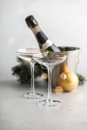 Téléchargez les photos : Bouteille de champagne dans un seau avec glace, verres et décorations de Noël sur fond de béton - en image libre de droit