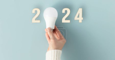 Téléchargez les photos : Main tenant une ampoule LED sur fond bleu. avec texte Concept d'ampoule économique et écologique. Idée - en image libre de droit