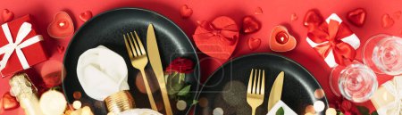 Photo for Romantic table setting, flat lay with black plates, red heart shape chocolate candies, candles, fork, knife, champagne, romantic gifts and flowers on red background. Valentine Day, love, dating - Royalty Free Image