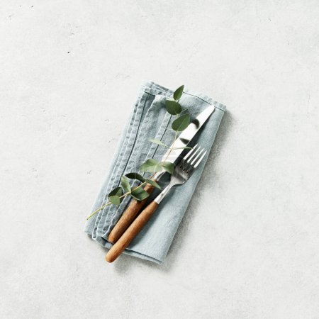 Foto de Ajuste de mesa con servilleta, tenedor, cuchillo y eucalipto sobre fondo gris composición cuadrada - Imagen libre de derechos