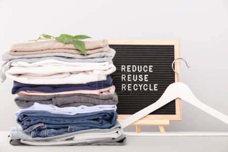 Black letter box and stack of folded clothes, reduce,reuse,recycle quote.  Zero waste sustainable lifestyle. Plastic free concept. 
