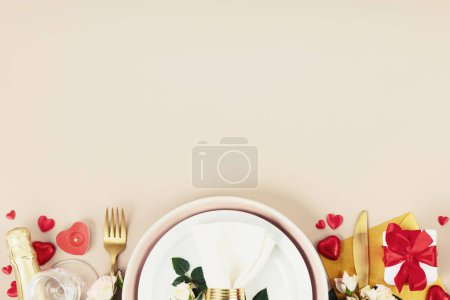Photo for Romantic table setting, flat lay with white plate, red heart shape chocolate candies, fork, knife, champagne, romantic gifts and flowers on beige background. Valentine Day, love, dating concept, copy - Royalty Free Image