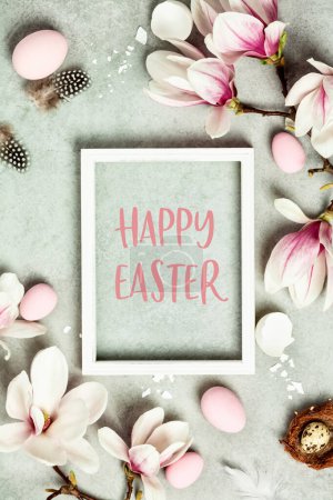 Photo for Easter mock up with Photo frame, space for text, beautiful spring magnolia flowers and Easter decorations on grey stone background. Flat lay, top view, copy space - Royalty Free Image
