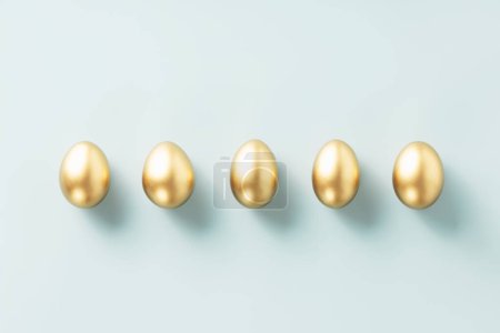 Foto de Una fila de huevos dorados sobre un fondo azul vista superior plana poner bandera - Imagen libre de derechos