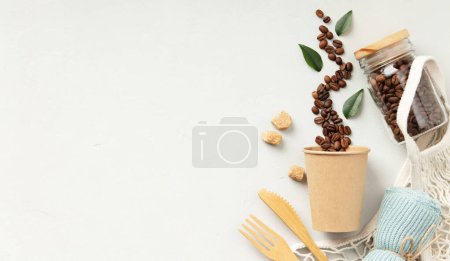 Téléchargez les photos : Café en grains renversé à partir d'une tasse en papier avec des ustensiles écologiques et un bocal sur blanc. - en image libre de droit