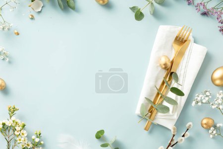 Téléchargez les photos : Décoration de table de Pâques. Cadre élégant de table de brunch de Pâques avec des œufs, des couverts dorés et des branches de printemps sur fond bleu - en image libre de droit