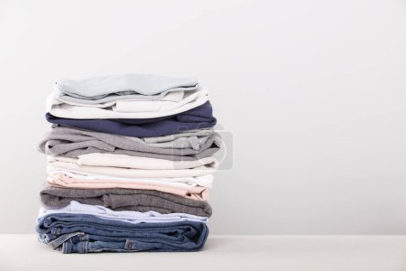 stack of folded clothes, grey background, copy space